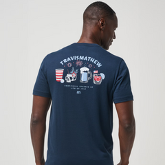A blue TravisMathew shirt with a beer pong cup, skull, beer glass, and cocktail glass on the back. With a phrase that says, "UNOFFICAL SPONSOR of 4th OF JULY."