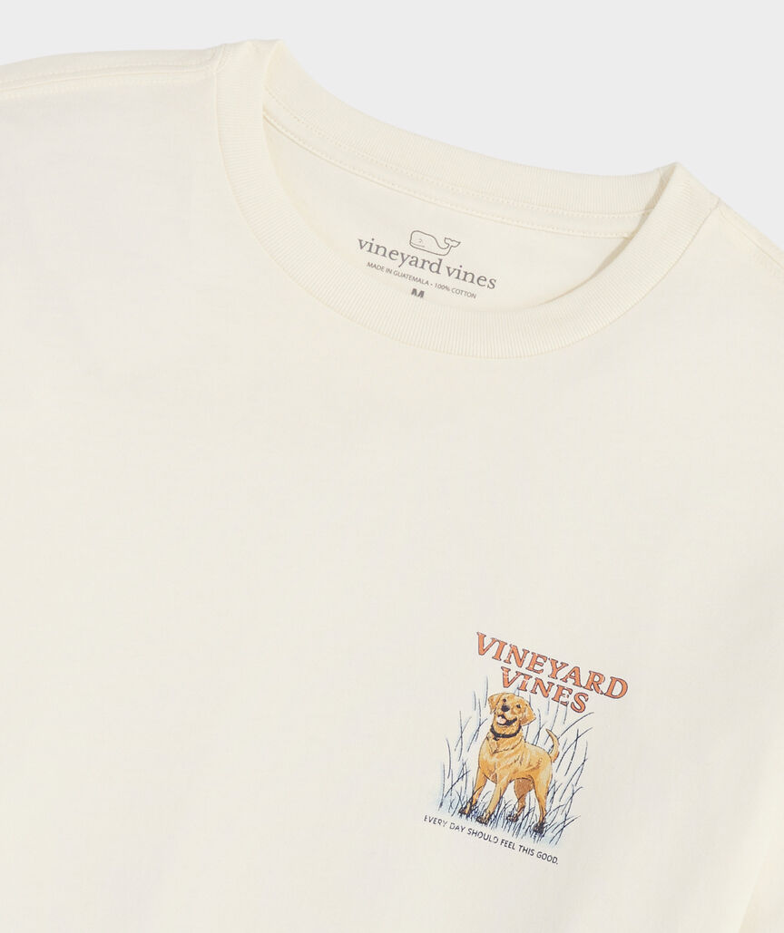 Long sleeve t-shirt with the graphic of a golden retriever dog on the back. Above the dogs is, "Vineyard Vines." Below the dog is the phrase, "EVERY DAY SHOULD FEEL THIS GOOD." The dog is standing in high grass, and the t-shirt is the color marshmallow. The t-shirt is tagless, and instead has the Vineyard Vines whale logo with the size of the shirt engraved into the collar.