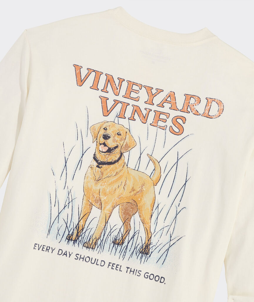 Long sleeve t-shirt with the graphic of a golden retriever dog on the back. Above the dogs is, "Vineyard Vines." Below the dog is the phrase, "EVERY DAY SHOULD FEEL THIS GOOD." The dog is standing in high grass, and the t-shirt is the color marshmallow.