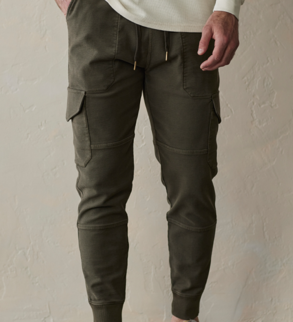 Front view of the Comfort Terry Jogger pants from The Normal Brand. Shown in color dusty olive green. The Jogger has draw strings at the waist, side pockets for your hands, and pockets on both legs.