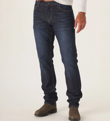 Front view of The Normal Jean from The Normal Brand in dark blue color. Being worn by a man in work boots.