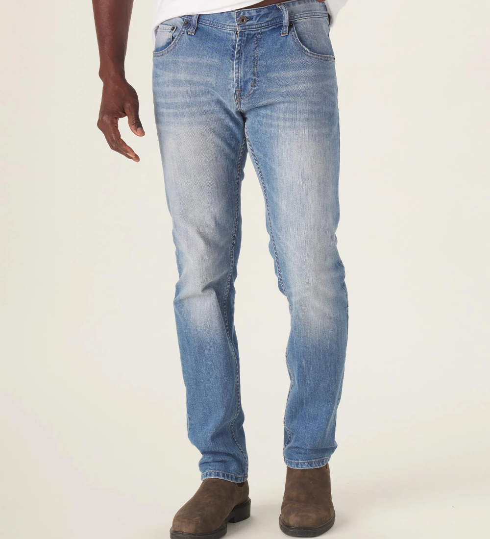 Front view of The Normal Jean from The Normal Brand in light wash color. Being worn by a man with work boots.