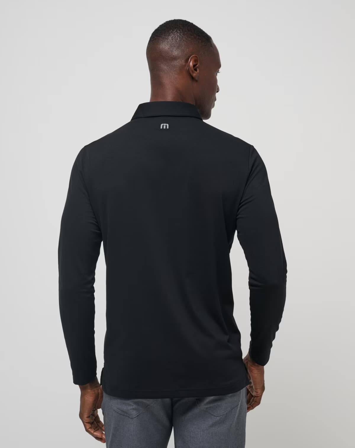 Course Mapper Long Sleeve Polo in all black. Featuring a grey stripe logo across the chest. The polo comes from the brand TravisMathew.