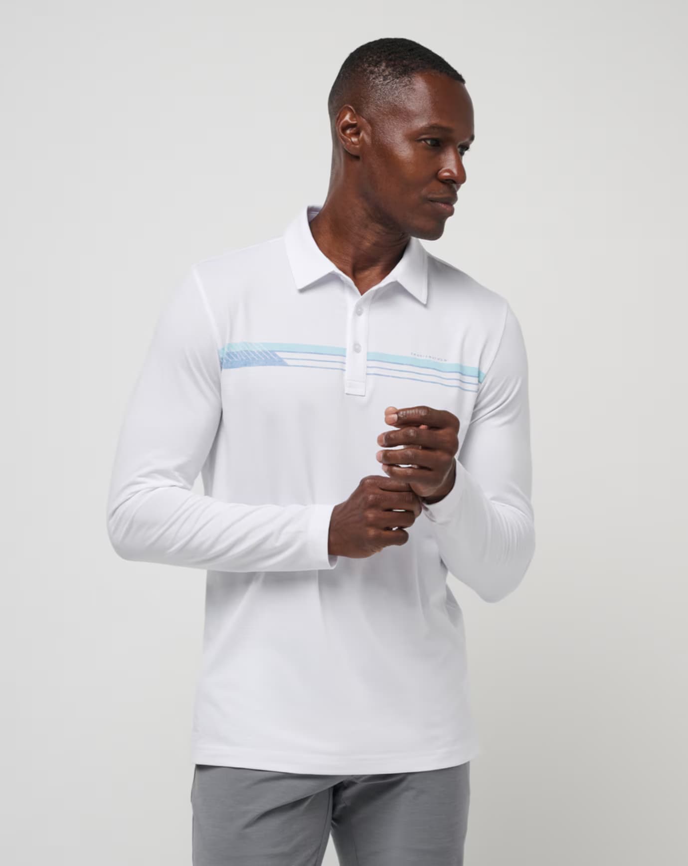 Course Mapper Long Sleeve Polo in all white. Featuring a blue stripe logo across the chest. The polo comes from the brand TravisMathew.