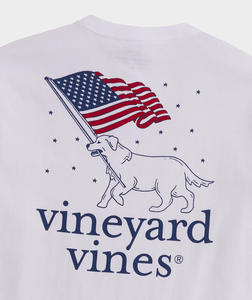 A Vineyard Vines pocket t-shirt showing a dog carrying an American flag in it's mouth.