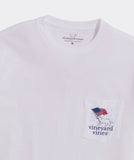 A Vineyard Vines pocket t-shirt showing a dog carrying an American flag in it's mouth.