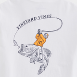 A white t-shirt from Vineyard Vines. Showing a fishermen wearing a yellow wet suit, riding a large mouth bass fish, with a fishing hook in front of it's mouth.