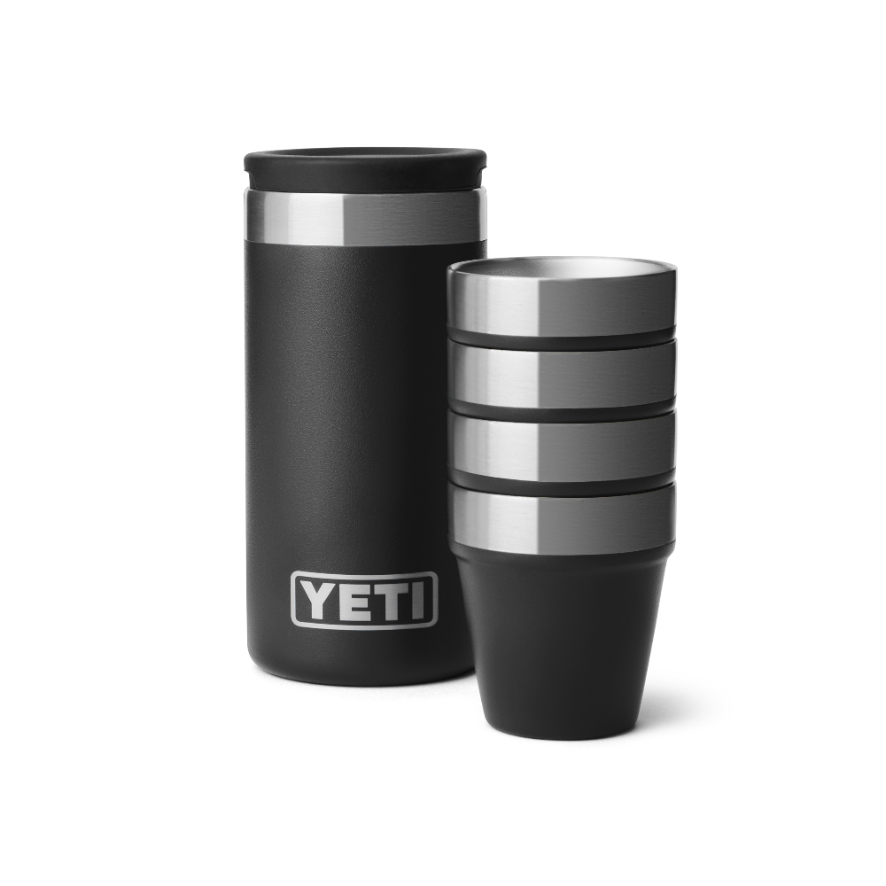 4 black shot glasses stacked together, sitting next to a black travel case with a silver YETI logo on the front.