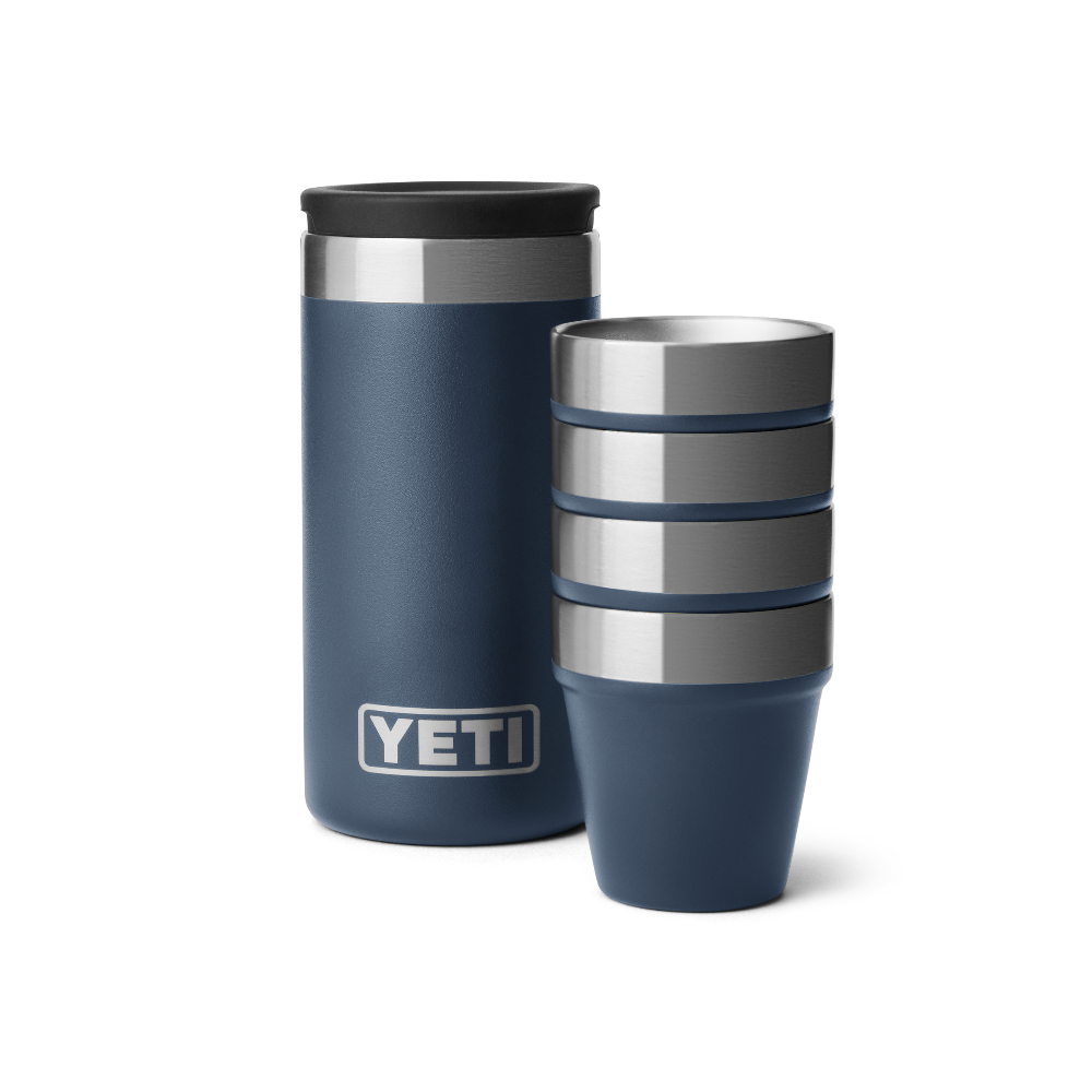 4 blue shot glasses stacked together, sitting next to a navy blue travel case with a silver YETI logo on the front.