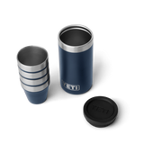 4 navy blue shot glasses stacked on top of one another, sitting next to a navy blue travel case with the lid taken off. The travel case has a silver YETI logo on the front.