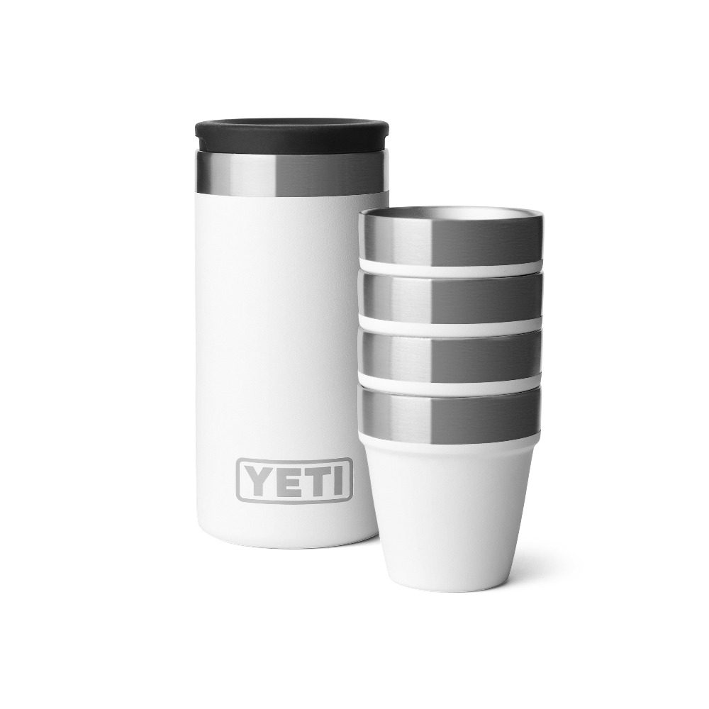 4 white shot glasses stacked together, sitting next to a white travel case with a silver YETI logo on the front.