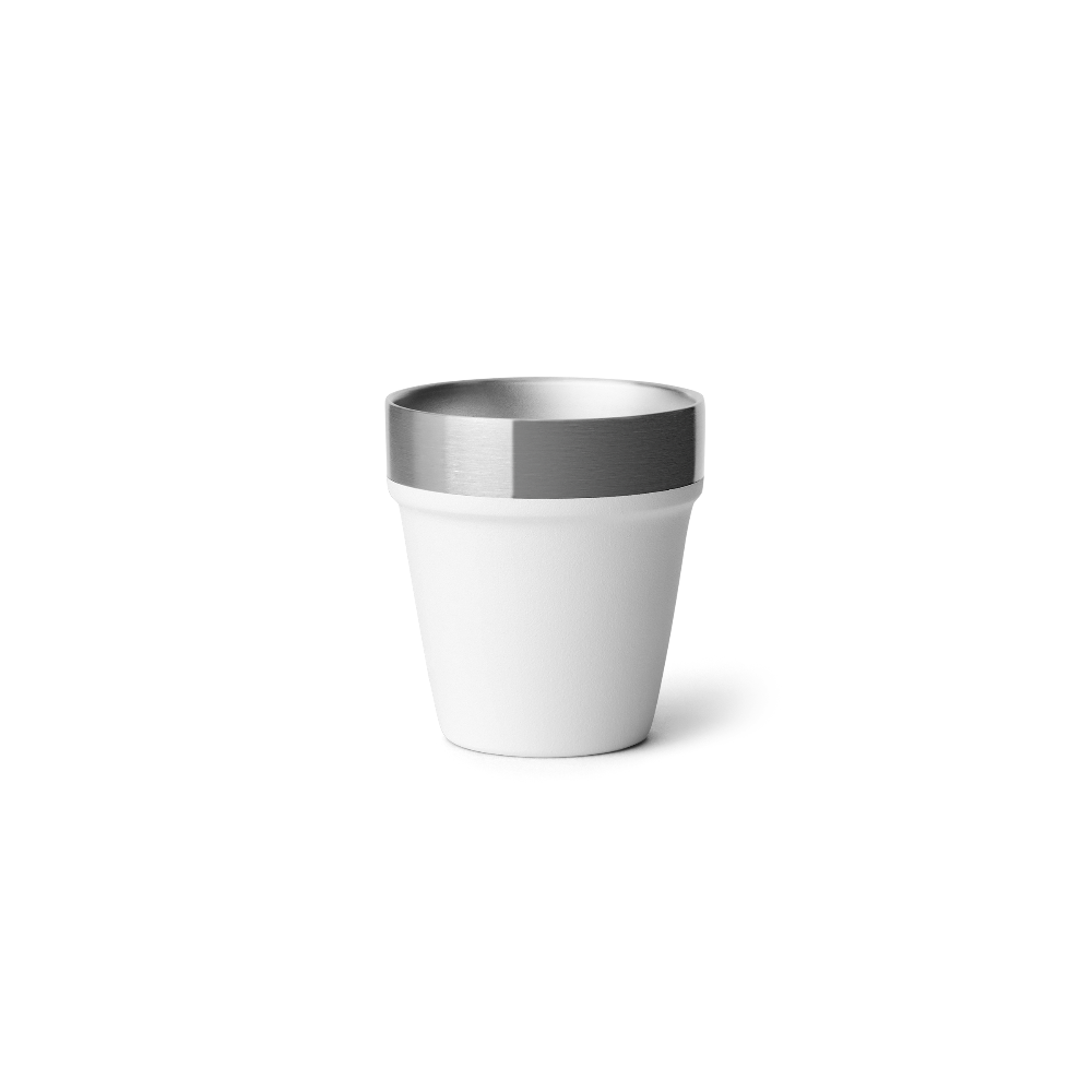 A white shot glass with a stainless steel rim on the top.