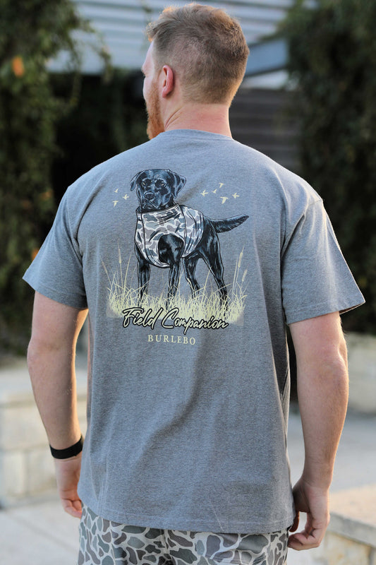 A Burlebo Men's Field Companion Short Sleeve Tee on a model. Showing the back of the shirt, with a black lab in a camo vest. 1080